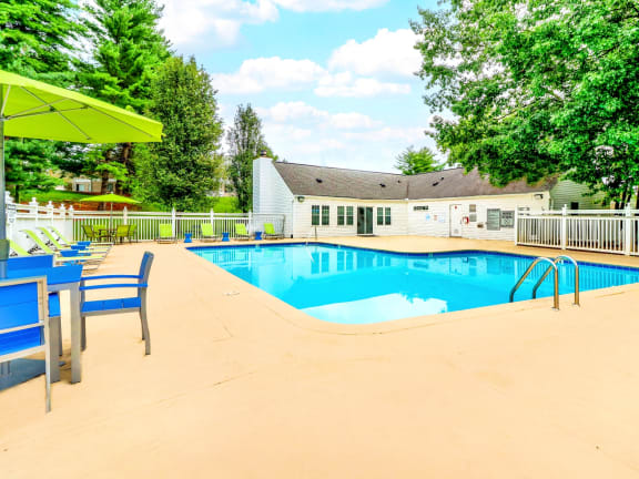 our resort style swimming pool is surrounded by chairs and tables