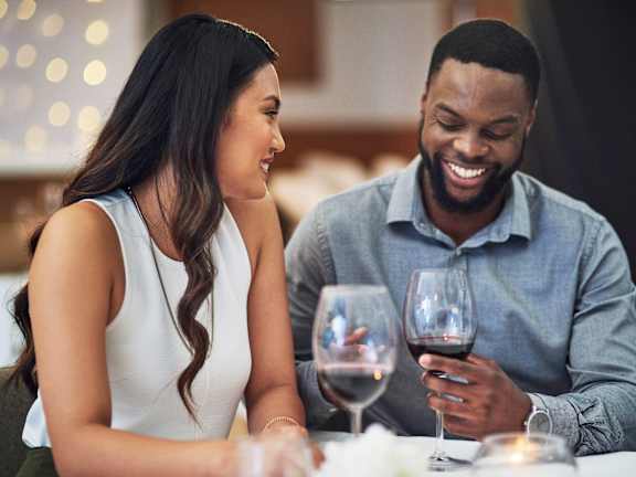 A man and a woman are sitting at a table with wine glasses in front of them.