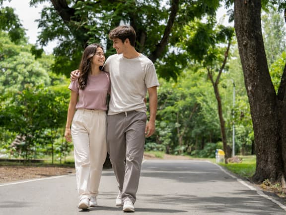 A couple walking down a tree-lined road.