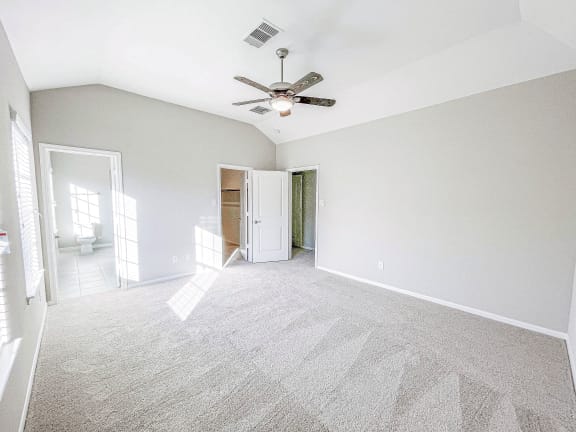an empty bedroom with a ceiling fan