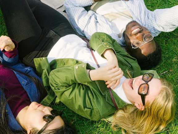 Three people lying on the grass.