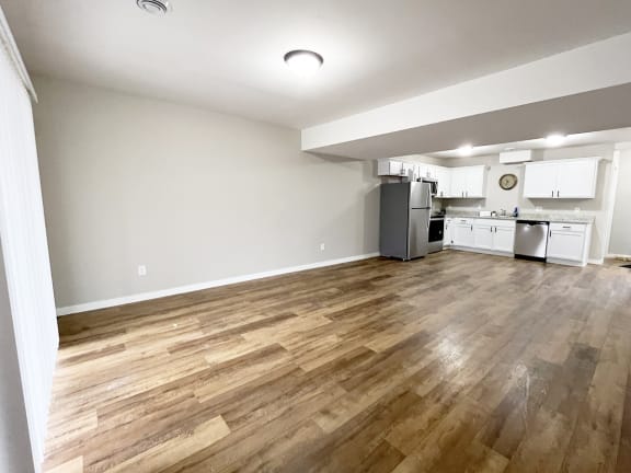 an empty living room and kitchen with wood flooring