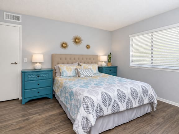A bedroom with a bed, nightstand, and window.
