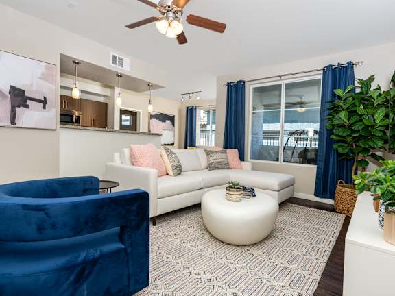 A living room with a blue velvet chair and a white sofa.