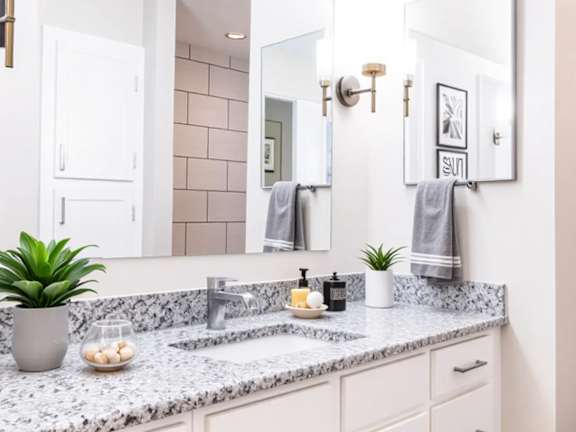A bathroom with a marble countertop and white cabinets.