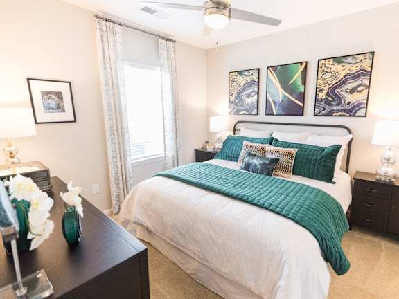 A bedroom with a large bed and a ceiling fan.