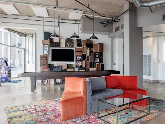 A modern living room with a television, speakers, and a colorful rug.