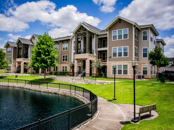 an exterior view of an apartment building with a small pond in front of it