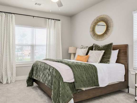 A bedroom with a bed, a dresser, and a window with curtains.