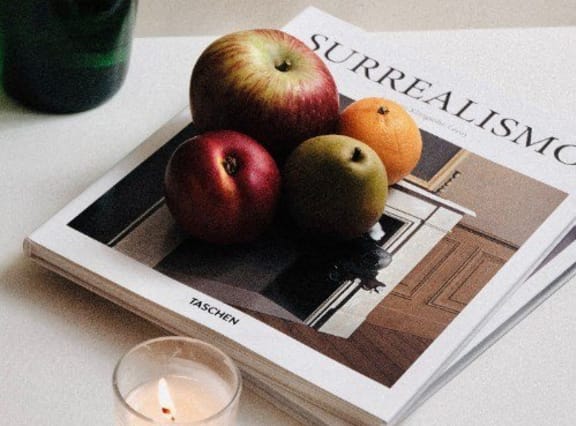 three apples sitting on top of a magazine on a table