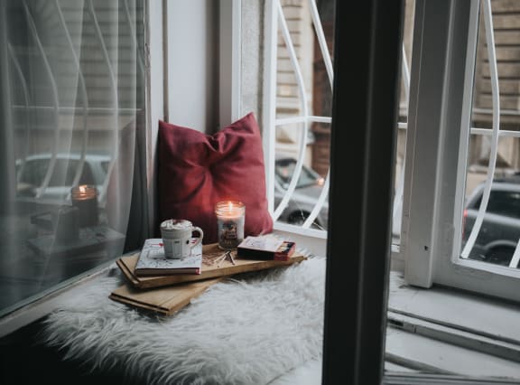a tray with a cup of coffee and a candle on a window sill