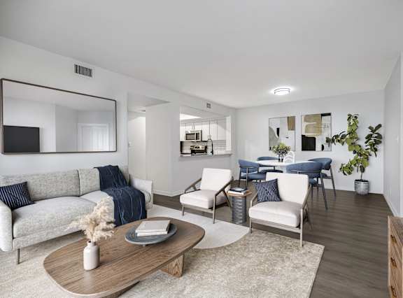 A modern living room with a white sofa, a wooden coffee table, and a large mirror on the wall.