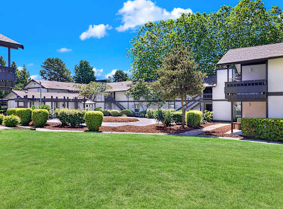 A sunny day at a residential complex with green lawns and trees.