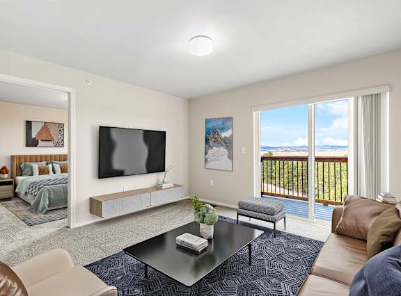 A living room with a television, a couch, a coffee table, and a balcony.