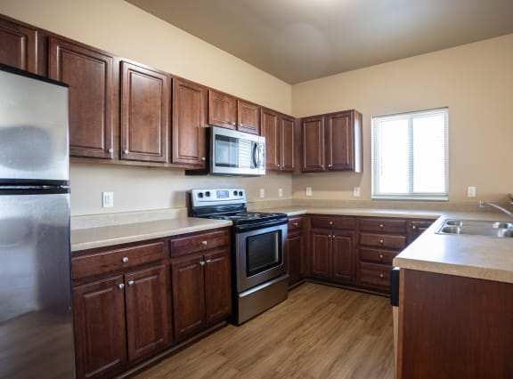 an empty kitchen with wooden cabinets and stainless steel appliances