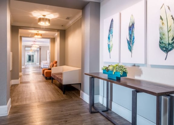 a long hallway with paintings on the wall and a table with plants at Linden on the GreeneWay, Orlando, 32824