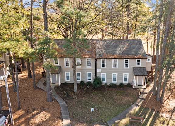 A house surrounded by trees in a forest at West Oak Apartments, North Carolina