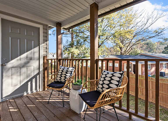 A wooden porch with two chairs and a table at West Oak Apartments, North Carolina 27587