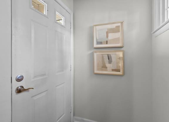 A white door with a silver handle and a picture frame on the wall at West Oak Apartments, Wake Forest, North Carolina