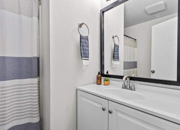 A bathroom with a white sink and a mirror at West Oak Apartments, Wake Forest