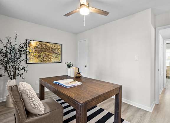 A room with a brown table and a plant on the left side at West Oak Apartments, Wake Forest