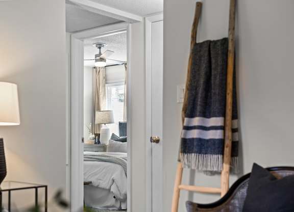 A bedroom with a bed, a lamp, and a blanket on a ladder at West Oak Apartments, Wake Forest