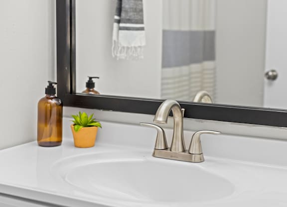 A bathroom sink with a silver faucet and two soap dispensers at West Oak Apartments, North Carolina