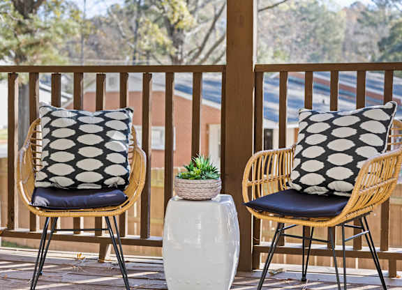 Two chairs with black and white pillows on a wooden balcony at West Oak Apartments, North Carolina