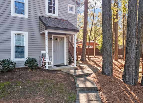 A small house with a white door and a porch at West Oak Apartments, Wake Forest, 27587