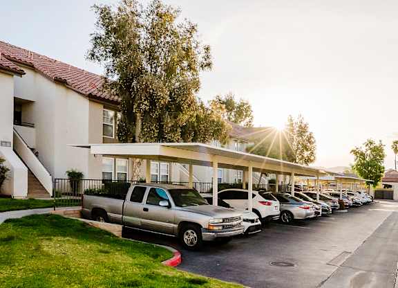 A parking lot with cars parked in front of a building with a tree in the background. at Legends at Rancho Belago, Moreno Valley, CA, 92553