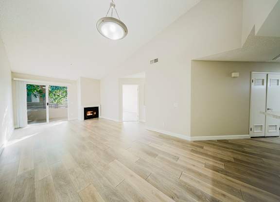 A spacious room with a fireplace and a door leading to another room. at Legends at Rancho Belago, Moreno Valley