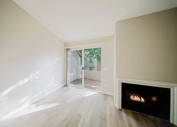 A room with a fireplace and a view of a tree-lined street through a glass door. at Legends at Rancho Belago, Moreno Valley, California
