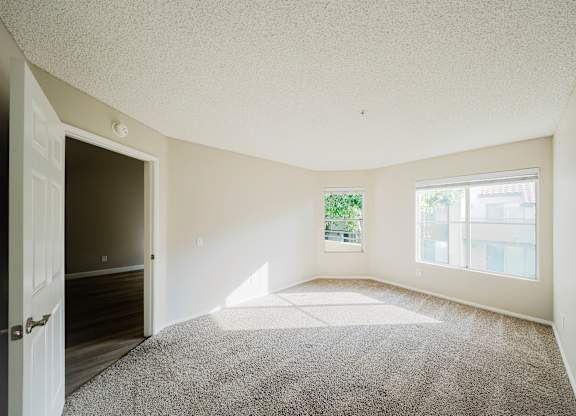 A room with a carpeted floor and a door leading to another room. at Legends at Rancho Belago, California