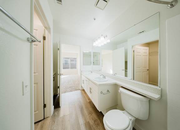 A white bathroom with a toilet, sink and mirror. at Legends at Rancho Belago, Moreno Valley, 92553