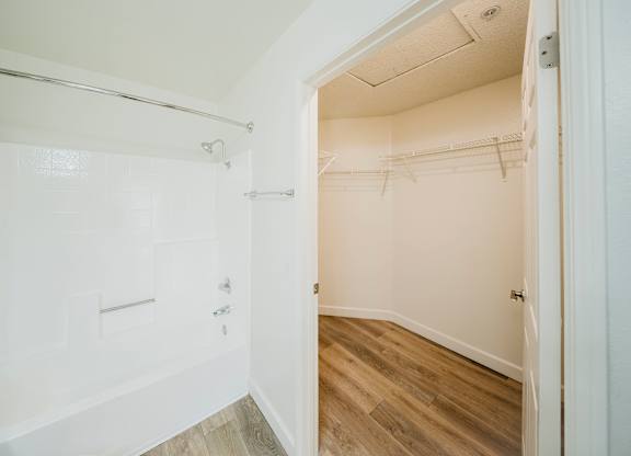 A white bathroom with a walk-in shower and a wooden floor. at Legends at Rancho Belago, Moreno Valley, California
