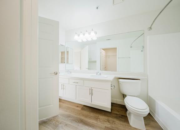 A white bathroom with a toilet, sink, and mirror. at Legends at Rancho Belago, Moreno Valley