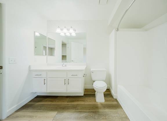A white bathroom with a toilet, sink, and mirror. at Legends at Rancho Belago, Moreno Valley, CA