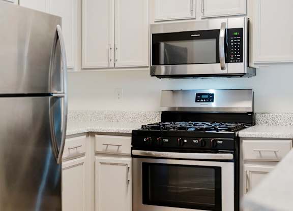 A modern kitchen with a stainless steel refrigerator, microwave, and stove. at Legends at Rancho Belago, Moreno Valley, CA
