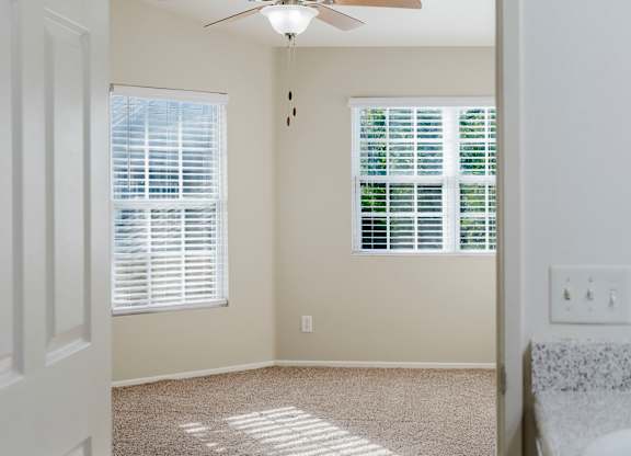 A room with a ceiling fan and two windows with blinds. at Legends at Rancho Belago, Moreno Valley, California