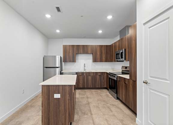 A kitchen with a white countertop and wooden cabinets.