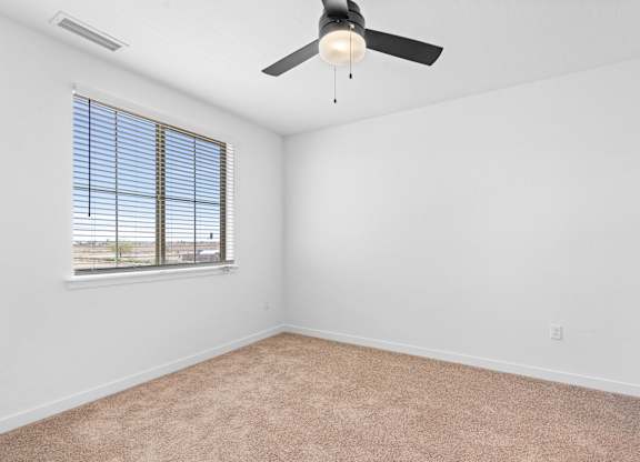A room with a ceiling fan and a window with blinds.