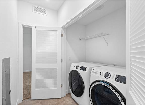 A white laundry room with two washing machines.