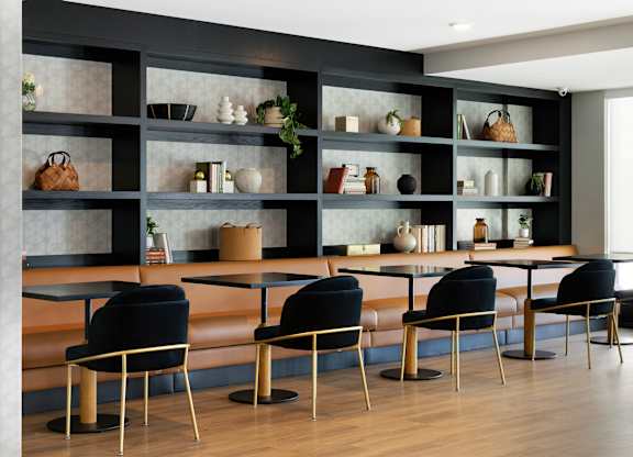 A modern dining area with black chairs and a black shelf with various items on it.