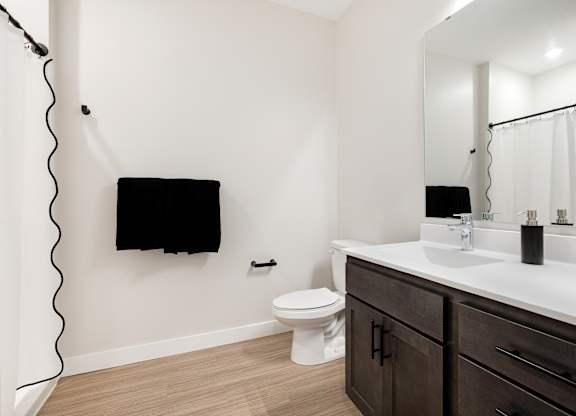 A bathroom with a toilet, sink, and mirror.