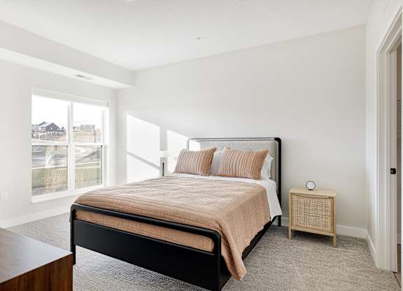 A bedroom with a large bed and a window overlooking a street.