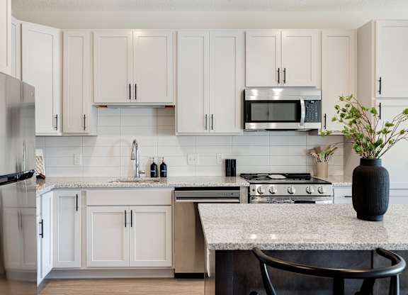 A kitchen with white cabinets and a granite countertop.