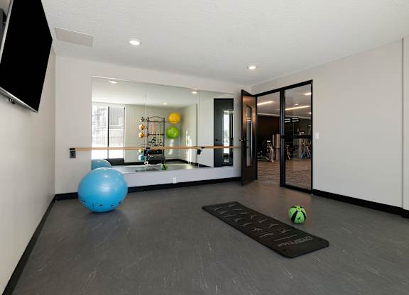 A blue exercise ball sits on a mat in a room with a mirrored wall.