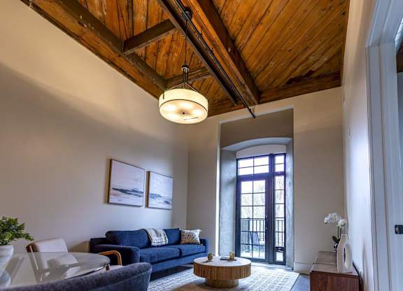 A living room with a blue couch and a wooden ceiling at The Dean at Creekview Apartments, Newark, Delaware