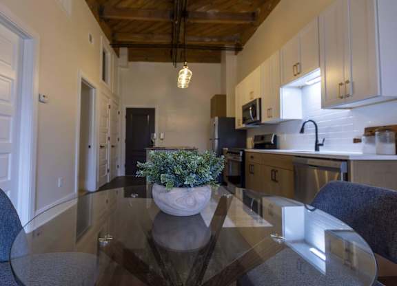 A kitchen with a table and chairs in the foreground at The Dean at Creekview Apartments, Newark, Delaware