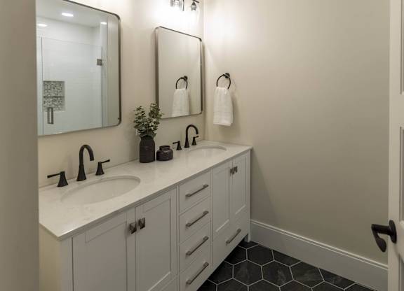 A bathroom with a sink, mirror, and a plant at The Dean at Creekview Apartments, Delaware